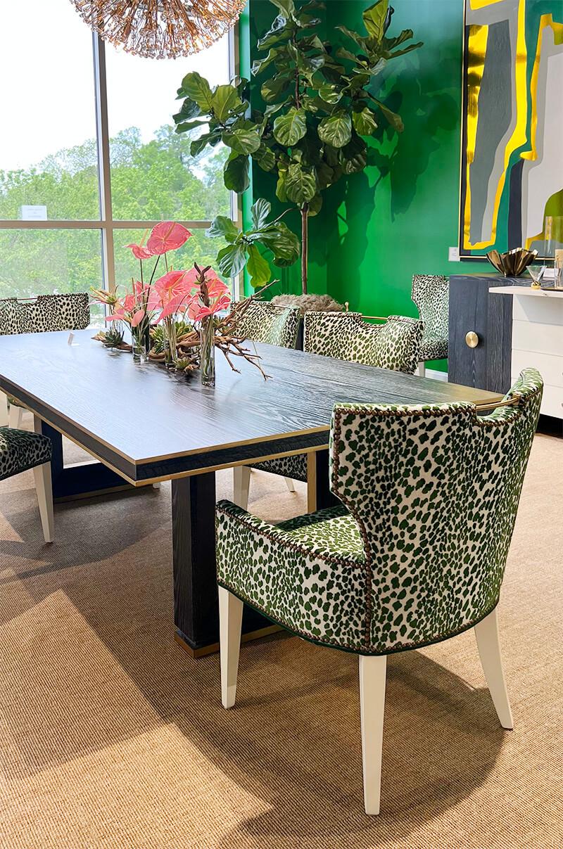 a dining table with chairs upholstered in green leopard print against a kelly green wall